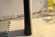 Tall, slender, textured cylindrical ceramic or wooden decorative object with a two-toned vertical or striped design, resembling modern art pottery or a candle holder.