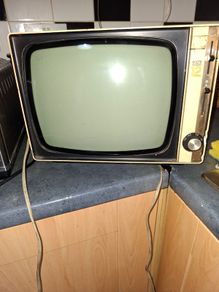 Ideal Prop, Vintage Working Boots Audio TV12 Portable Black and White CRT Television, featuring a cream plastic casing with side control dials and a 12 inch screen. Designed with dual power capabilities supporting standard mains voltage (240V) as well as 