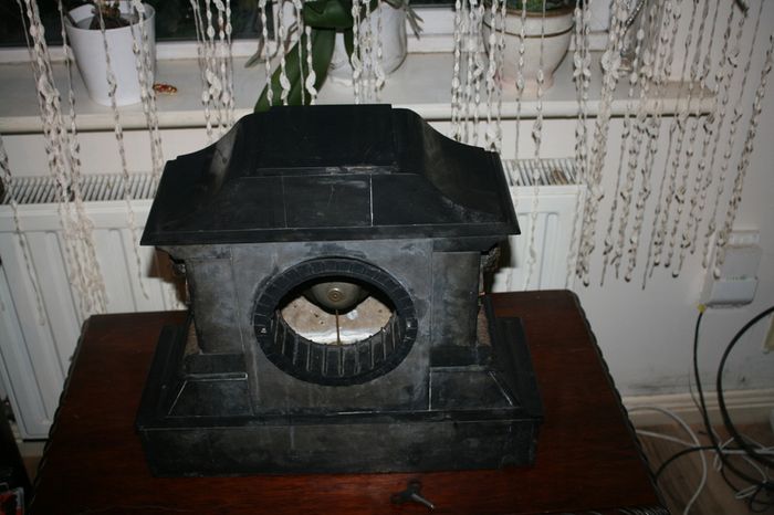 Victorian French Black Slate Mantle Clock (Very large and heavy) with bronze ornamentation Oversized. Open escarpment slate plate Roman numerals. Circa 1890s. Accented with Trojan head. Flanked by two Hellenistic ladies heads on sides. Rose cartouche mask