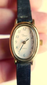 Vintage Timex womens quartz watch - gold tone oval case, white dial and black strap