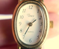 Vintage Timex womens quartz watch - gold tone oval case, white dial and black strap
