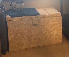 Double bed with headboard and separate storage trunk.