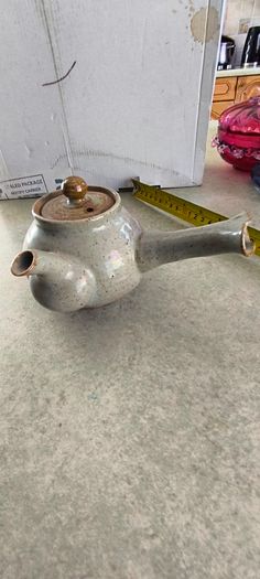 Japanese Side-Handle Teapot Kyusu 300cc  speckled ceramic side-handle teapot (kyusu) features a hand-painted pink cherry blossom (sakura) or plum floral branch motif against a light gray or cream stoneware body