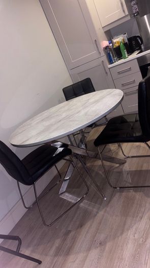 Round marble-effect dining table with 4 black chairs