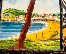 Hand painted tile from Palamos, Playa La Fosca La Fosca beach in Palamos, Costa Brava, Spain. heled in black costirorn holder