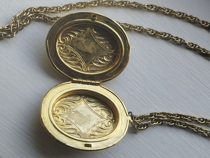 A large medallion featuring religious symbols, suspended from a long chain.