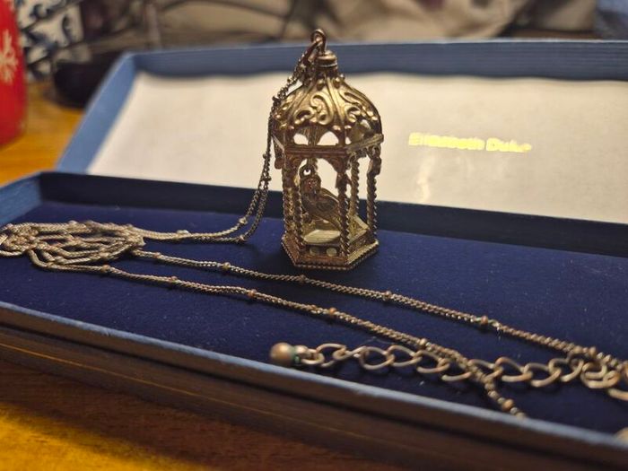 Vintage gilded bird cage with a bird pendant.
