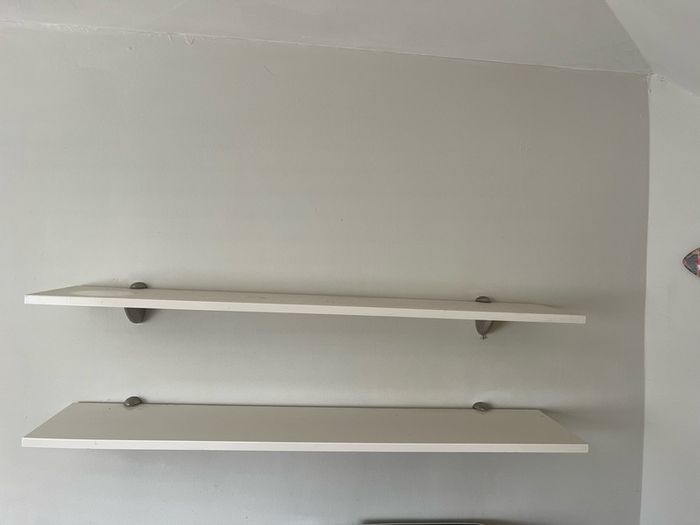 A pair of e floating wall shelves mounted on decorative metal shelf brackets.