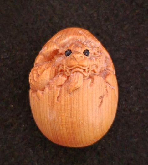 Carved wooden dragon hatching from an egg.