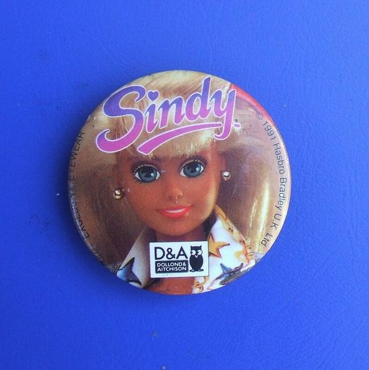 DOLLOND & AITCHISON (high-street opticians) - a promotional button badge featuring a Sindy doll (1990s)