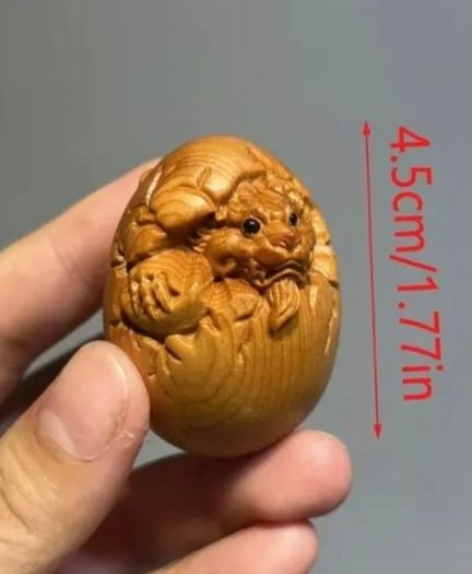 Carved wooden dragon hatching from an egg.