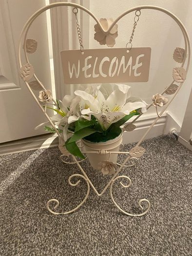 White welcome sign on stand, with artificial flower