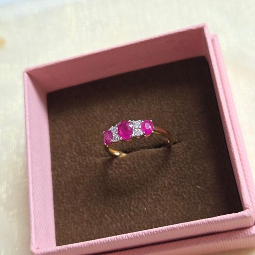 Beautiful yellow gold ring featuring three stunning rubies surrounded by sparkling cubic zirconia stones. Size M, in beautiful condition.