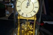 West Germany Estyma Anniversary Clock, featuring a brass finish and a rotating pendulum under a Glass Dome,