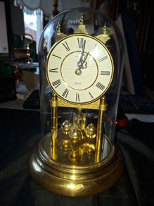 West Germany Estyma Anniversary Clock, featuring a brass finish and a rotating pendulum under a Glass Dome,