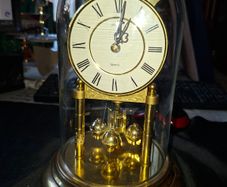 West Germany Estyma Anniversary Clock, featuring a brass finish and a rotating pendulum under a Glass Dome,