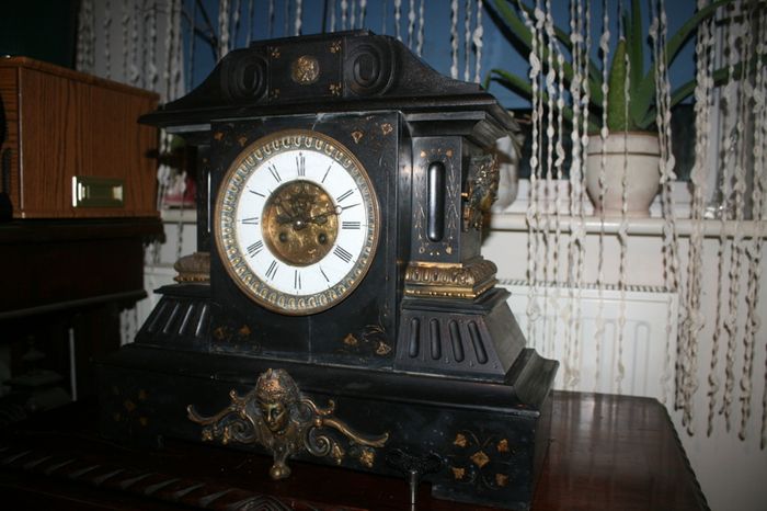 Victorian French Black Slate Mantle Clock (Very large and heavy) with bronze ornamentation Oversized. Open escarpment slate plate Roman numerals. Circa 1890s. Accented with Trojan head. Flanked by two Hellenistic ladies heads on sides. Rose cartouche mask