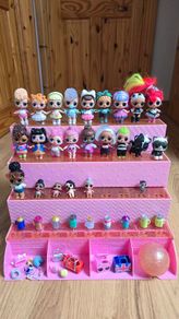 A lot of L.O.L. Surprise dolls with accessories and a doll podium.