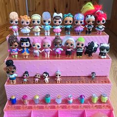 A lot of L.O.L. Surprise dolls with accessories and a doll podium.