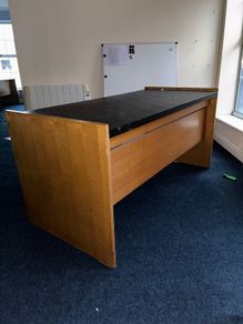 Large wooden reception desk with black countertop
