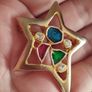 A gold star-shaped brooch. Image 2