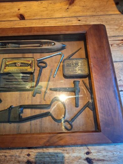 vintage shadow box containing a mix of antique tools, keys, and a loom.