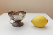 Small silver plated bowl with handles cast as lion's head holding a ring
