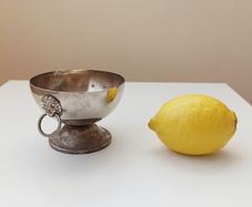 Small silver plated bowl with handles cast as lion's head holding a ring