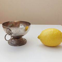 Small silver plated bowl with handles cast as lion's head holding a ring
