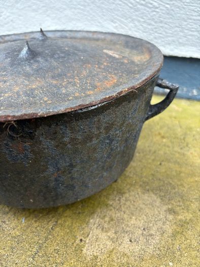 Antique cast iron tri-legged dutch oven and lid.