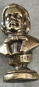 This brass bust appears to be a vintage docertive item / paperweight and pipe tamper or desk accessory depicting the composer Schubert, featuring his name clearly inscribed on the base.