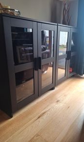 2 black cabinets with glass doors and shelves