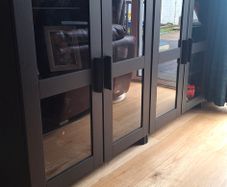 2 black cabinets with glass doors and shelves