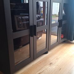 2 black cabinets with glass doors and shelves