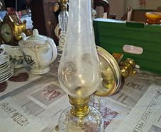 Old Oil lamp with Reflector Mirror, Clear Glass Base and a Tall Glass Chimney. It includes a brass burner, commonly used for wall mounting. Similar models are often categorized as Kerosene or Hurricane Lamps and can be used on tables or walls