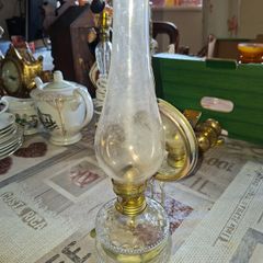 Old Oil lamp with Reflector Mirror, Clear Glass Base and a Tall Glass Chimney. It includes a brass burner, commonly used for wall mounting. Similar models are often categorized as Kerosene or Hurricane Lamps and can be used on tables or walls