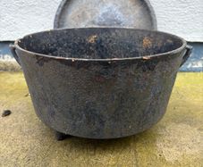 Antique cast iron tri-legged dutch oven and lid.