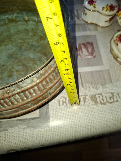 Antique Copper Cauldron features a Rustic Patina, a Swing Handle, and Distinctive Ribbed Detailing around the Rim. It resembles vintage metal pots often used for hearth decoration or as Planters. The piece shows significant oxidation and aging, characteri