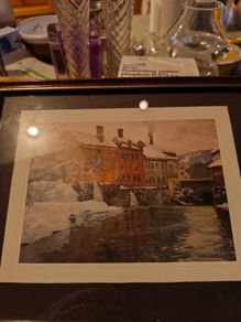 Framed print of  Snow-Covered Buildings by a River by Fritz Thaulow (1847 - 1906).