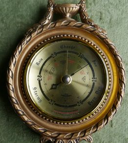 Vintage barometer with silvered dial mounted in an ornate gilt frame.
