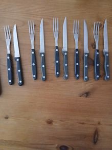 A 12-piece stainless steel steak knife and fork set with wooden riveted handles.