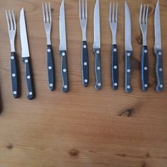 A 12-piece stainless steel steak knife and fork set with wooden riveted handles.