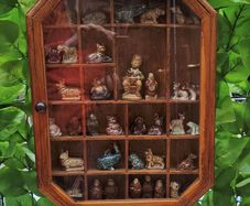 vintage glass display wall cabinet with Wade collection figurines