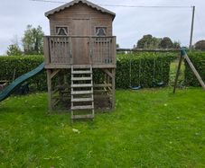 Wooden playhouse with slide and swings