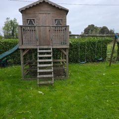 Wooden playhouse with slide and swings