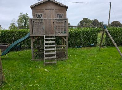 Wooden playhouse with slide and swings