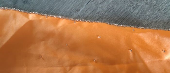 Solid orange satin look piece of fabric with beads