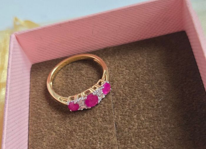 Beautiful yellow gold ring featuring three stunning rubies surrounded by sparkling cubic zirconia stones. Size M, in beautiful condition.