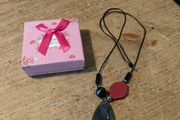 necklace featuring a striped black agate gemstone pendant and a distinct red geometric bead.
