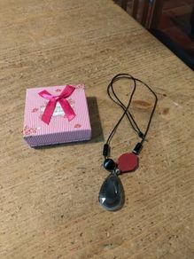 necklace featuring a striped black agate gemstone pendant and a distinct red geometric bead.